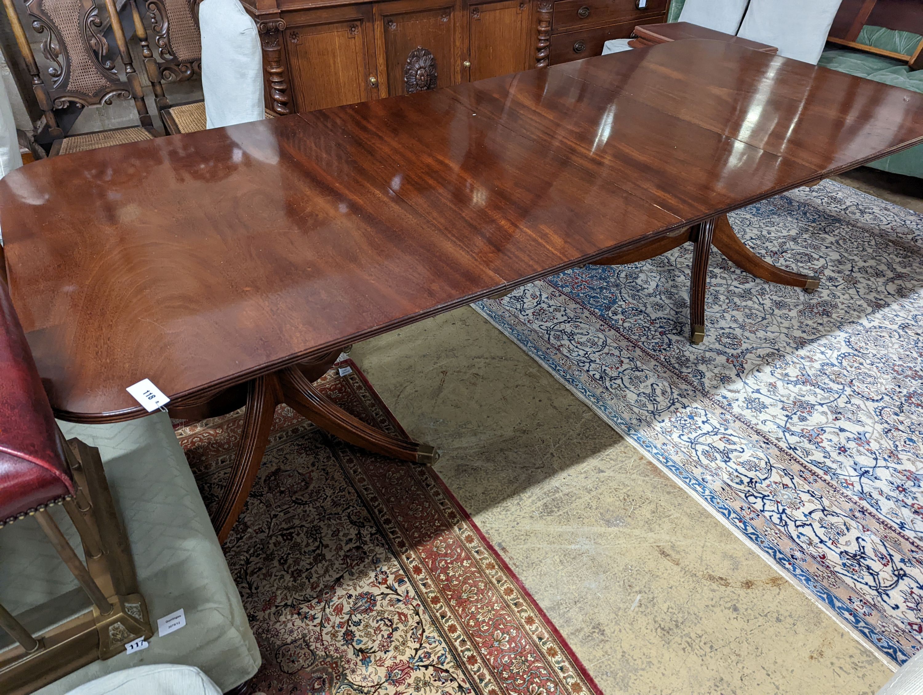 A reproduction George III style mahogany twin pillar extending dining table, two spare leaves, length 244cm extended, width 107cm, height 73cm